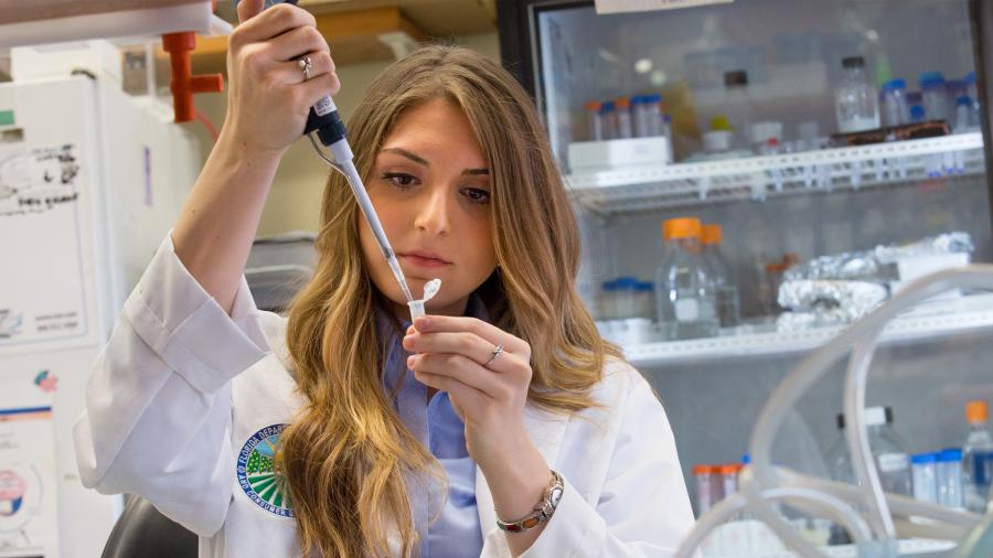 Woman pipetting in lab wearing a Florida Department of  Agriculture and Consumer Services lab coat