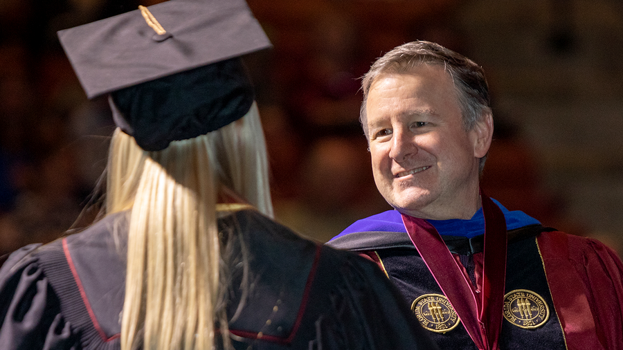 President Richard McCullough shakes a student's hand at Commencement