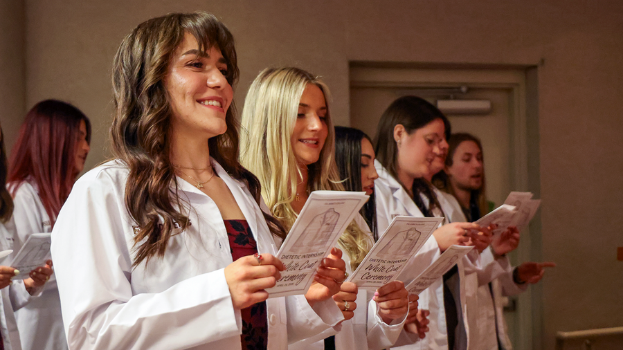 Students seen wearing white coats reading an oath