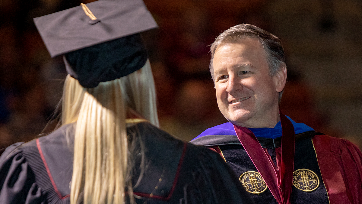 President Richard McCullough shakes a student's hand at Commencement