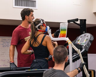 woman on treadmill running while wearing a performance testing mask