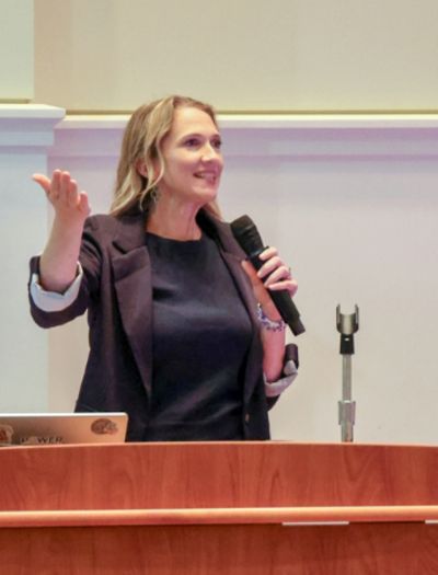 Jenny Root speaks at a podium in the College of Medicine auditorium