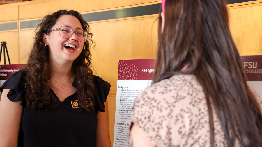 Student sharing research next to a poster