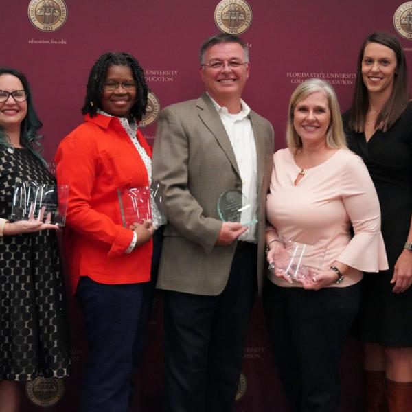 Seven people standing with awards