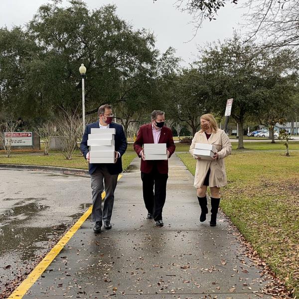 Three people walking in the rain holding care packages